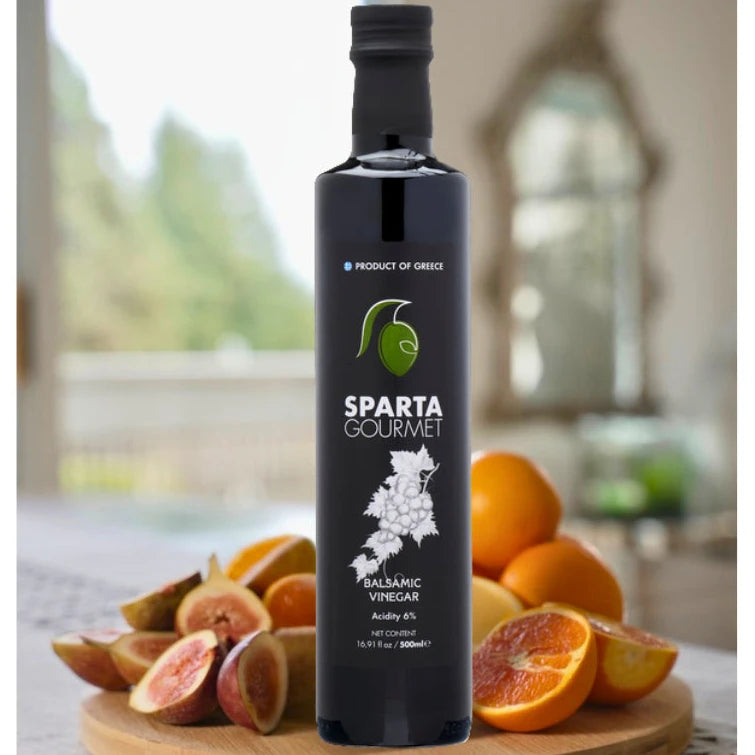 Sparta Gourmet balsamic vinegar bottle on a wooden cutting board with fruits in a kitchen setting