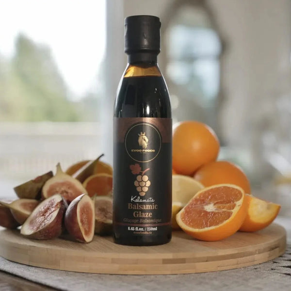 Bottle of Kalamata Balsamic Glaze on a wooden board with fruits in a bright setting